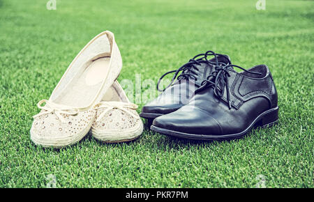 Women's and men's wedding shoes on the green grass. Symbol of love. Blue photo filter. Stock Photo