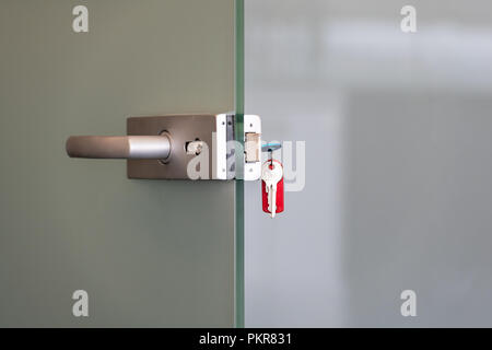 Modern glass door with metal alloy handles and key chain in lock, home or office security concept Stock Photo