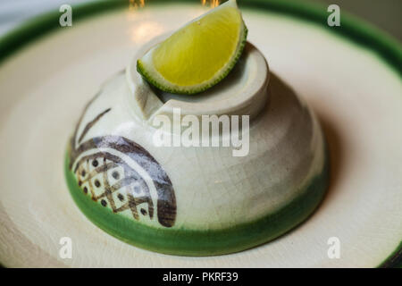 Lime slice and cut in to small pieces, places on a white ceramic plate and with salt for dipping. With vodka in a shot glass. Stock Photo
