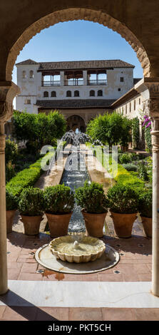 View of The Generalife courtyard, with its famous fountain and garden through an arch. Alhambra de Granada complex at Granada, Spain, Europe on a brig Stock Photo