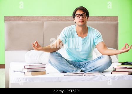 Student preparing for exams at home in bedroom sitting on the bed Stock Photo