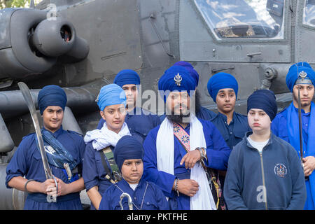 London 15th September 2018 UK Army open day to mark annual Saragarhi Commemorations This celebrates an epic battle where 21 Sikh soldiers took a last stand against 10,000 enemy tribesmen in 1897  A Sikh community leader with his traditional guards beside an apache attack helicopter Credit Ian Davidson/Alamy Live News Stock Photo