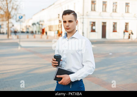 Handsome manager man with coffee and notepad walking in the city Stock Photo