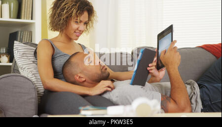 African couple using tablets on couch Stock Photo