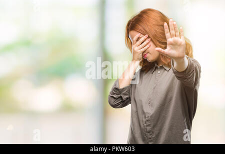 Young beautiful woman over isolated background covering eyes with hands and doing stop gesture with sad and fear expression. Embarrassed and negative  Stock Photo