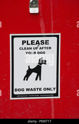 Close-up of red dog waste bin with sign asking people to please clean up after your dog Stock Photo