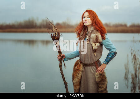 Pagan woman is a shaman, in her hands a sorcerer's staff for performing rituals. Stock Photo