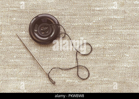 the composition of the seamstress, the tailor, the sewing thread and for knitting, the gray thread and the needle and the button Stock Photo