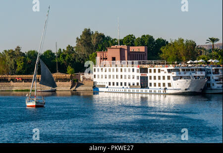 Moored tourist cruise ships on River Nile with traditional felucca sailing boat, Aswan, Egypt, Africa Stock Photo