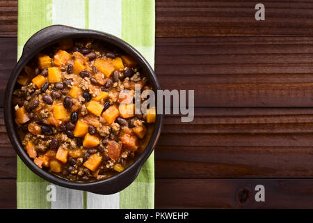 Homemade chili con carne with mincemeat, red and black beans, tomato sauce and pumpkin in rustic bowl, photographed overhead with copy space Stock Photo