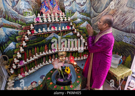 A Hindu pandit worshipping in a small temple in the basement of his home where he lead a congregation. In South Richmond Hill, Queens, New York. Stock Photo