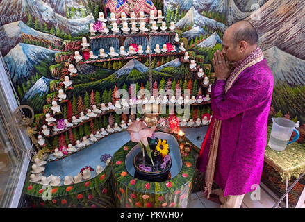 A Hindu pandit worshipping in a small temple in the basement of his home where he lead a congregation. In South Richmond Hill, Queens, New York. Stock Photo