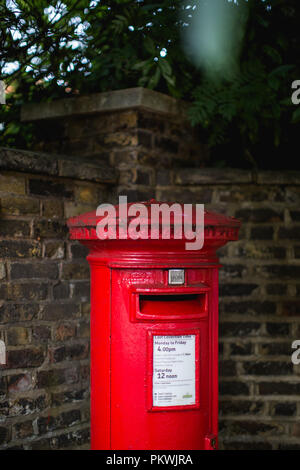 A bright red cast iron traditional British post box owned by Royal Mail UK and still in use Stock Photo