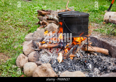 Cooking meal in kettles on burning campfire at wild camping Stock Photo ...