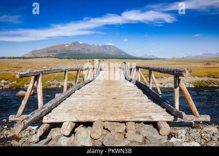 Wooden bridge over a river with distant mountain range in background, Altai Mountains, Western Mongolia Stock Photo