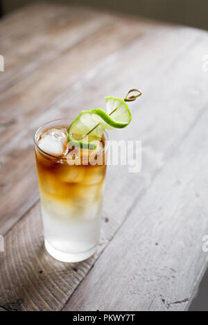 Dark and Stormy Rum Cocktail with Ginger Beer and Lime garnish. Glass of Dark and Stormy Cocktail drink on wooden table, copy space. Stock Photo