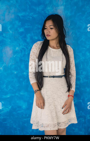 Portrait Of Beautiful Young Woman Standing Against Blue Background. Stock Photo