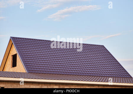 The roof of the house is covered with burgundy metal tile Stock Photo