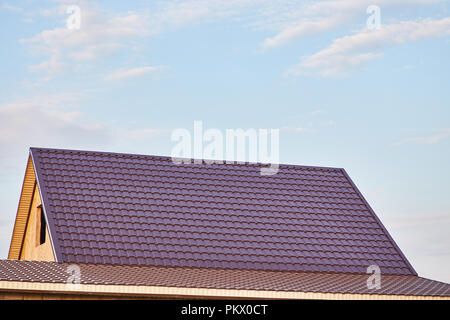 The roof of the house is covered with burgundy metal tile Stock Photo