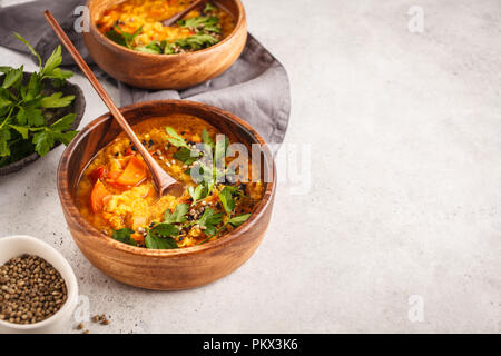 Yellow Indian vegan lentil soup curry in a wooden bowl, white background, top view. Stock Photo