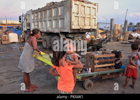 Cebu, Philippines-October 18, 2016: Filipino mother takes her children home in a flatbed trolley through the debris of a business day-Carbon Market-lo Stock Photo