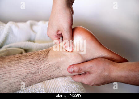 Massage relax studio. Foot massage. Close up of foot receiving massage in spa salon. Man receives leg massage. Therapists hands massaging male foot. Stock Photo