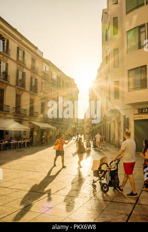 Spain, Malaga - 24 June 2017: a group of people walking down a street during sunset Stock Photo