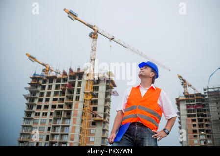 Proud architect on a construction site with buildings and cranes in the background Stock Photo