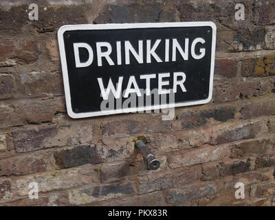 A sign posted on a brick wall indicating there is a water tap Stock Photo