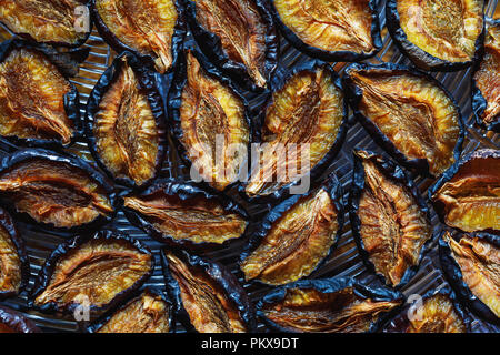 Fruits of prunes spread out on the dryer, top view. Background of healthy food Stock Photo