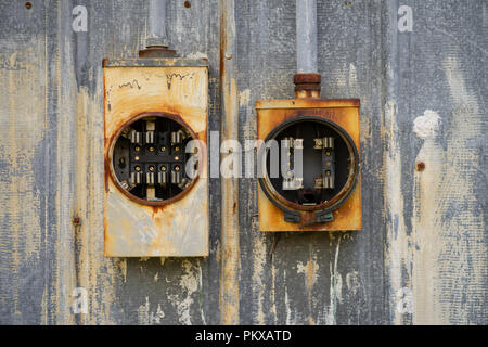 Two old electrical boxes sit empty of fuses and unused outside rusting in the elements Stock Photo