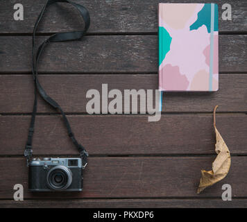 Autumn background on a wooden table with an old camera, autumn leaves and notepad. Lay flay Stock Photo