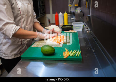 woman Cook prepares sushi on restaurant kitchen Stock Photo