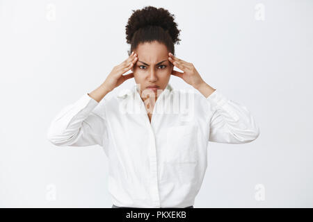 Woman trying focus, searching solutions in brain, being great strategist. Portrait of intense businesswoman trying concentrate, frowning, holding hands on temples, thinking hard to find solution Stock Photo