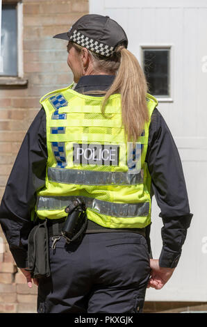 Female police officer in uniform a rear view showing baton Stock Photo