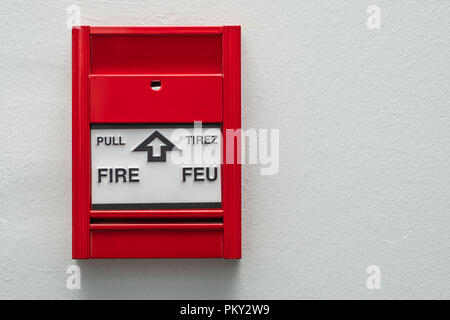 Fire alarm pull station mounted on a neutral coloured wall.
