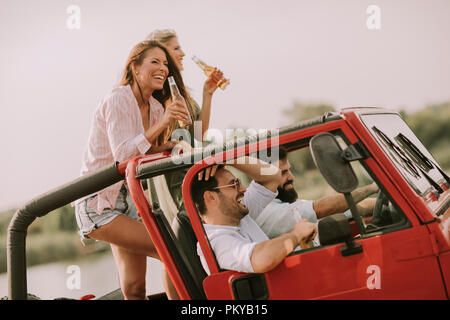 Happy friends having fun in convertible car at vacation by river Stock Photo