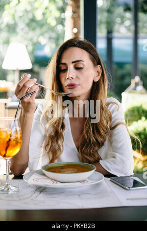 Young  attractive woman eating soup in restaurant