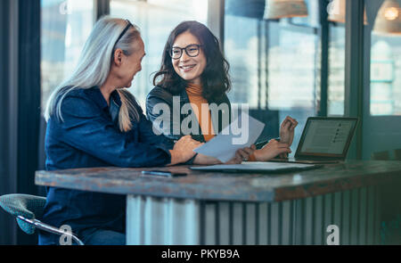 Happy businesswomen having a meeting in office. Two business colleagues discussing business matters. Stock Photo