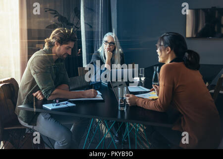 Business team sitting inside a meeting room and discussing work. Professionals sitting around a table brainstorming ideas. Stock Photo