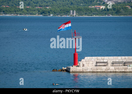 Croatian flag flying in wind on lighthouse in harbor Stock Photo