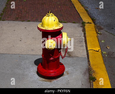 Red and yellow fire hydrant on sidewalk next to street. Stock Photo