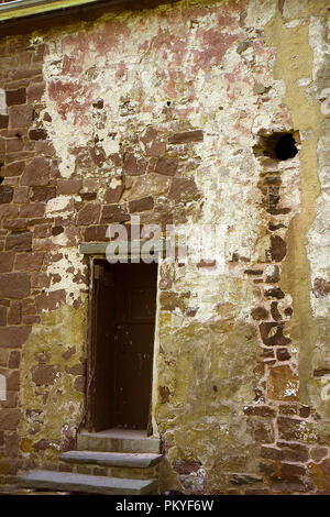 Backside wall of old historic building in New Castle, Delaware with door entrance. Brick is old and worn showing age. Stock Photo