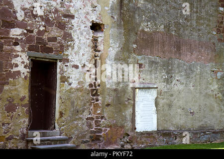 Backside wall of old historic building in New Castle, Delaware with door entrance. Brick is old and worn showing age. Stock Photo
