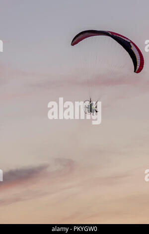 Paramotor in flight against the sky illuminated by the colors of a beautiful sunset Stock Photo