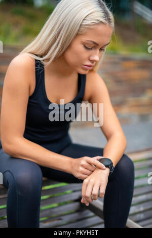 Woman Taking A Break After Workout And Checking Time On Smartwat Stock Photo