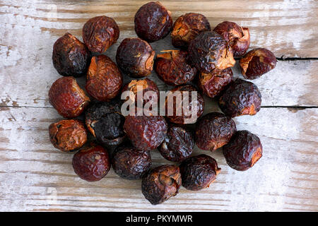 Heap of soap nuts on wooden background. Close-up. Stock Photo