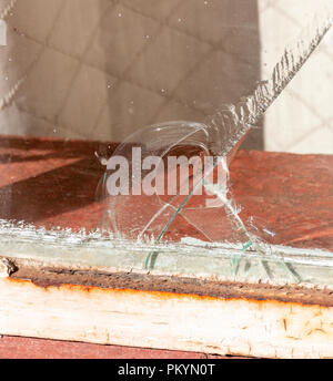 A close up view of a large crack in a lounge window where the glass has chiped and fallen away at the bottom Stock Photo