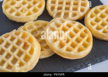Round small waffles on black slate board with selective focus Stock Photo