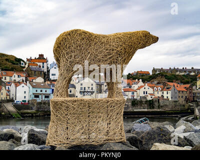 A large osier sculpture of a Polar Bear by Whitby sculptor Emma Stothard on the rock wall in Staithes Harbour Yorkshire during the annual art festival Stock Photo